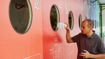 Man deposits a plastic bottle into a large colorful recycling station wall.