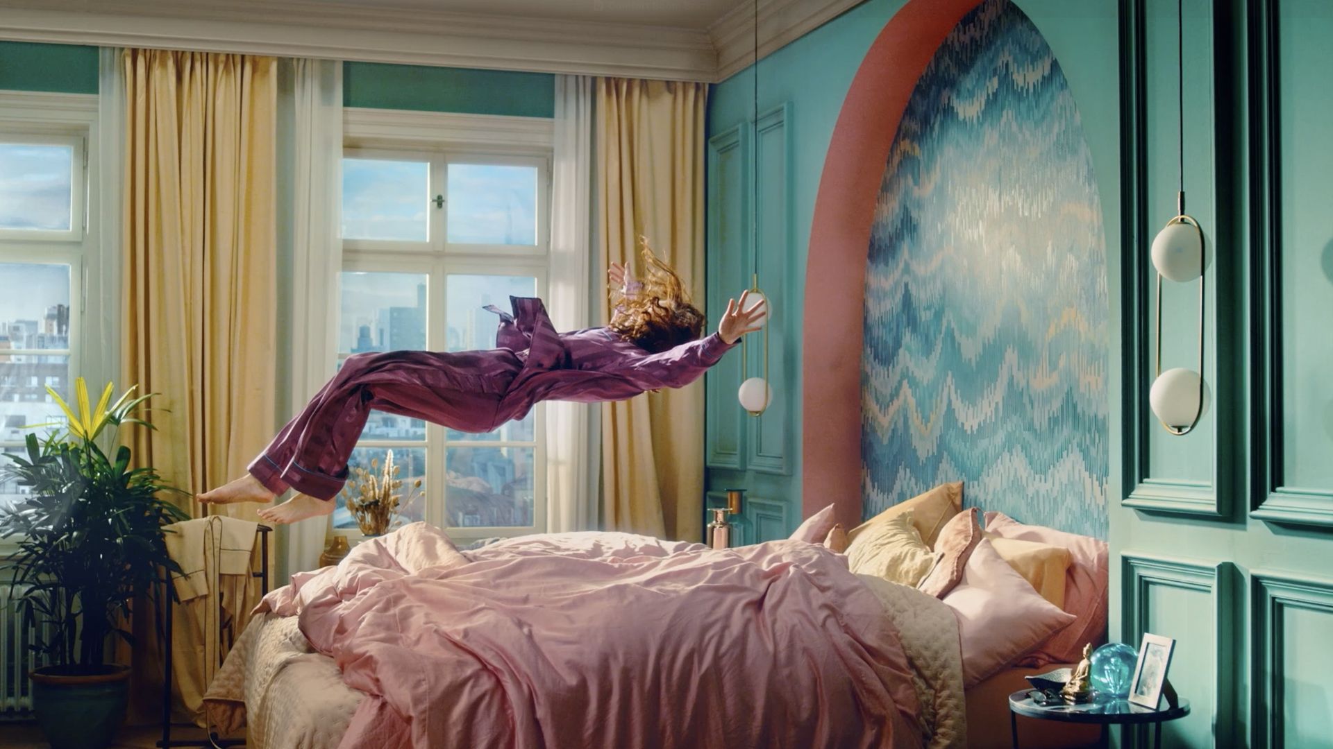 Person floating in a colorful bedroom with pink bedding